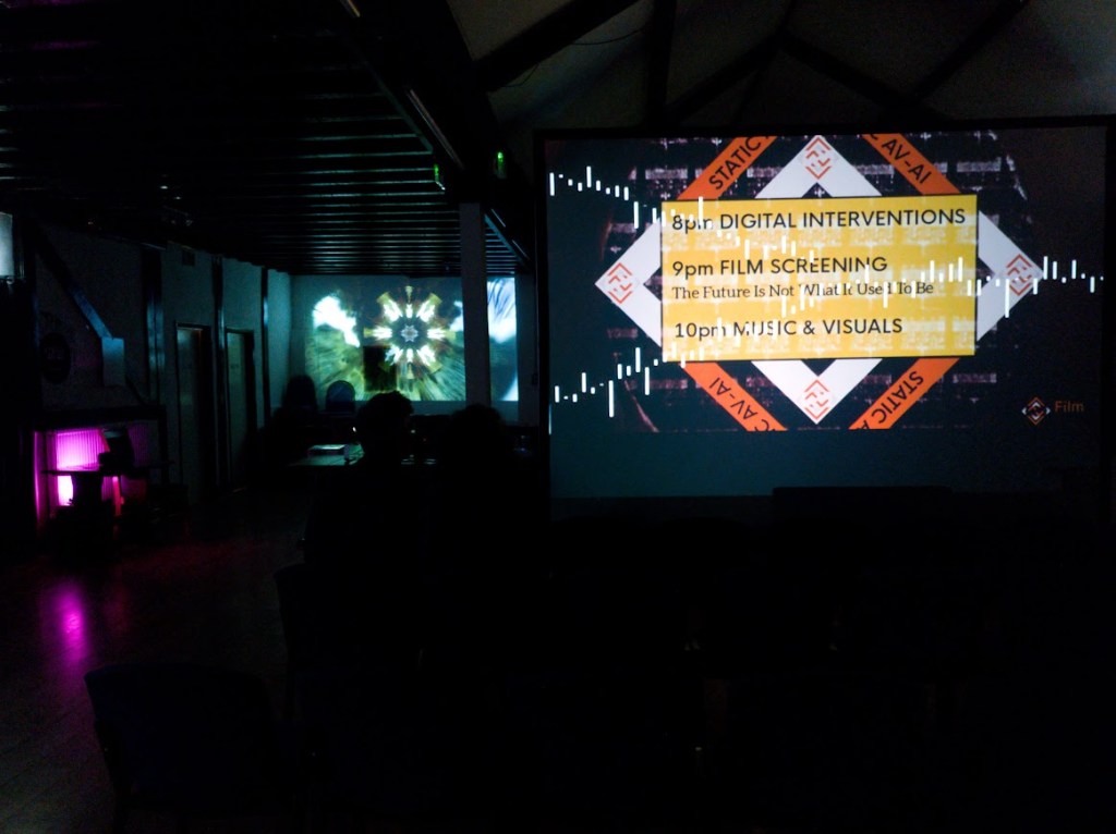 Inside the Herdsman venue on the night of AV - AI. Multiple projection screens show abstract imagery.