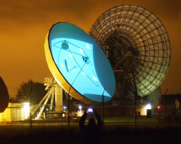 A satellite dish at Madley. The surface of the dish is lit up with projections.