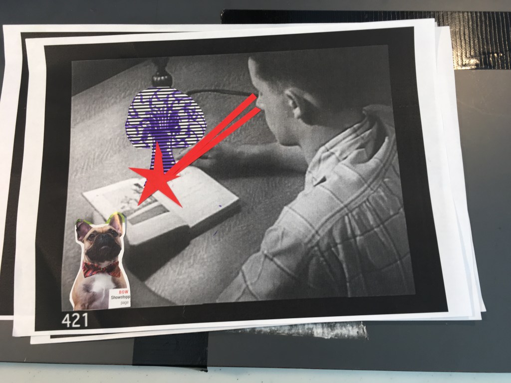 Printed paper featuring a boy reading a book. Laser beams have been made using red card which has been added to create the illusion of laser eyes.